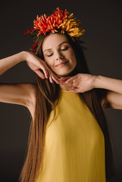 beautiful and brunette woman with closed eyes in wreath isolated on black - Fotó, kép