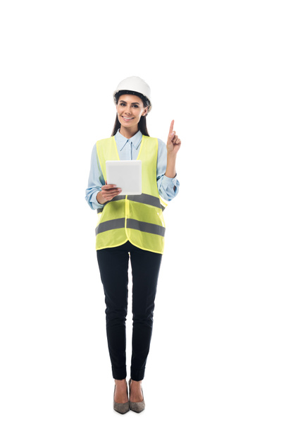 Full length view of engineer in safety vest using digital tablet and pointing with finger isolated on white - Photo, Image