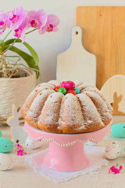 Zelfgemaakte vanille cake met gekleurde folie verpakt chocolade-eieren snoep op Pasen tafel - Foto, afbeelding