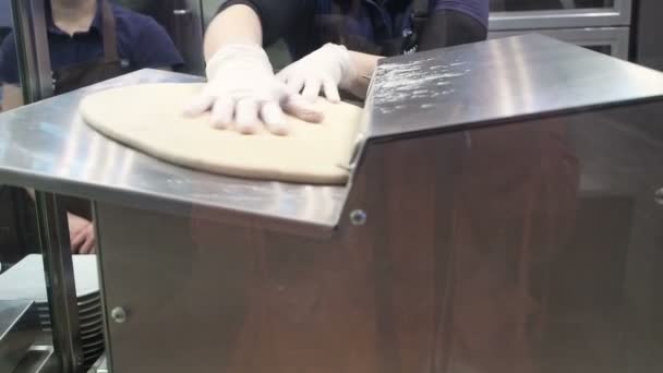 Η σκηνή: μάγειρας περνά η ζύμη μέσω σφολιατομηχανή, διαμορφώνοντας τη ζύμη κυλώντας μηχανή. Παραγωγή ρολά κανέλας. Προϊόντα αρτοποιίας. Κολλώδης ψωμάκια νόστιμα ψωμάκια κανέλλας  - Πλάνα, βίντεο