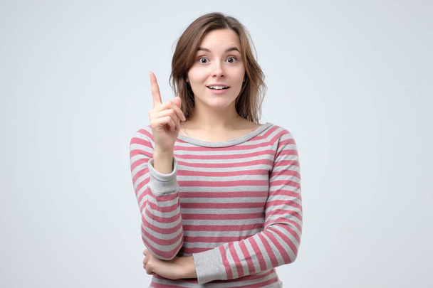 lächelndes europäisches Mädchen, das mit erhobenem Zeigefinger Ratschläge gibt. - Foto, Bild