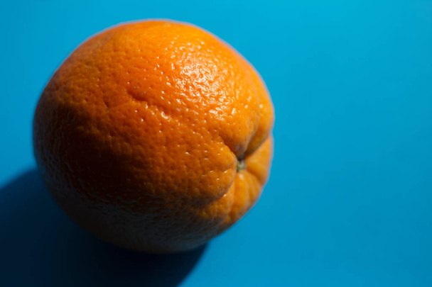 Pomerančový plod na modrém pozadí se stínem. - Fotografie, Obrázek