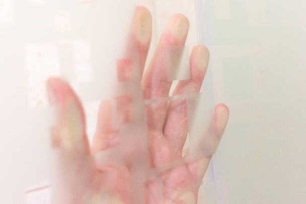 Sombra de mano detrás del vidrio esmerilado. Oscuridad artística y textura añadida
 - Foto, imagen