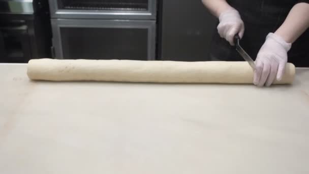 Η σκηνή: μάγειρας κόβει σε ίσα μέρη του ψωμάκια με κανέλα. Παραγωγή ρολά κανέλας. Προϊόντα αρτοποιίας. Κολλώδης ψωμάκια νόστιμα ψωμάκια κανέλλας  - Πλάνα, βίντεο