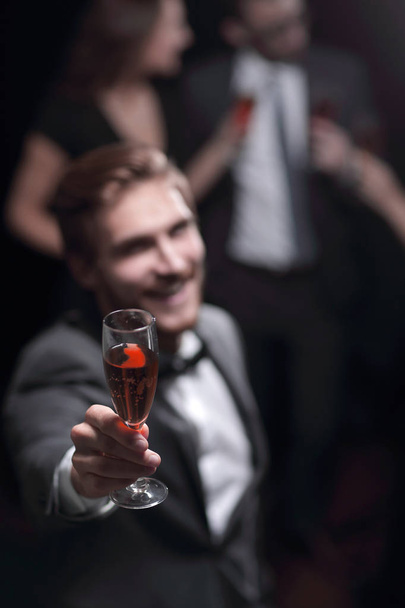 stylish young man standing with a glass of champagne. - Photo, Image