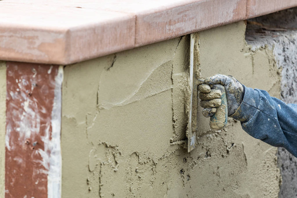 Плитка працівник застосування цементу з шпателем в басейн будівництва сидіти - Фото, зображення