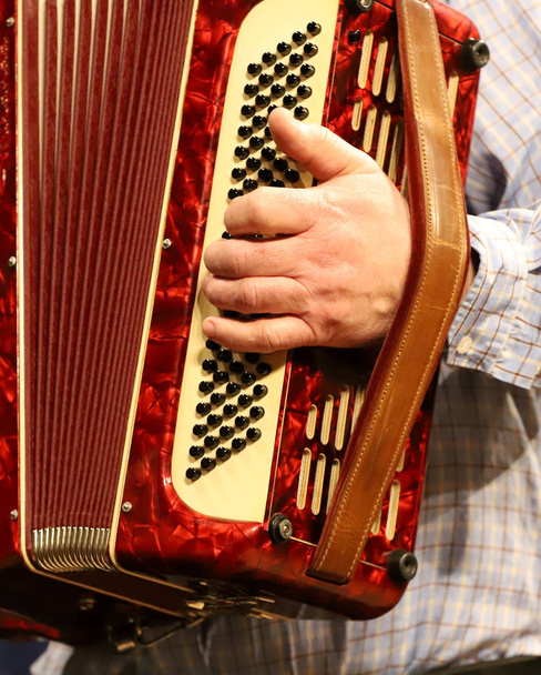 Man playing accordion.Playing the accordion, you can see a lot of buttons and hands of a senior. - Photo, Image