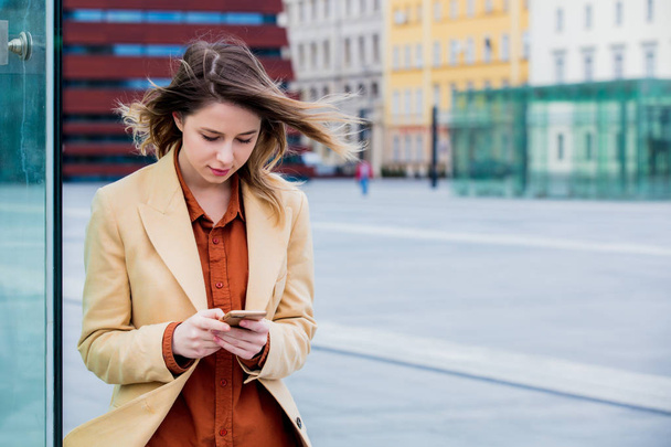junge Geschäftsfrau tippt telefonisch Nachricht auf dem Stadtplatz mit modernem Gebäude im Freien - Foto, Bild