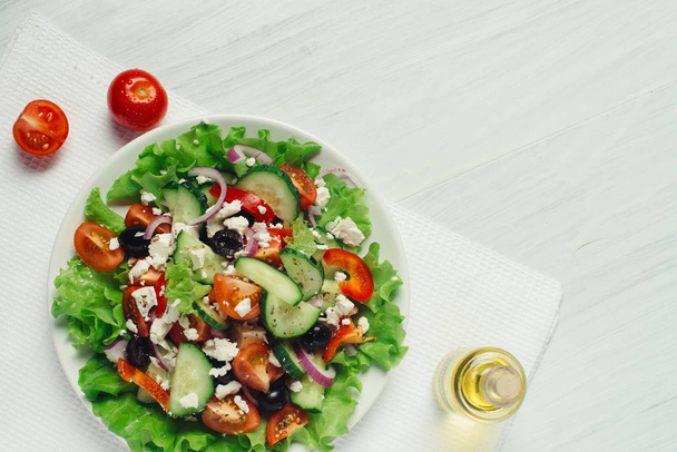 griechischer Salat mit Olivenöl und Tomaten auf weißer Tischplatte - Foto, Bild