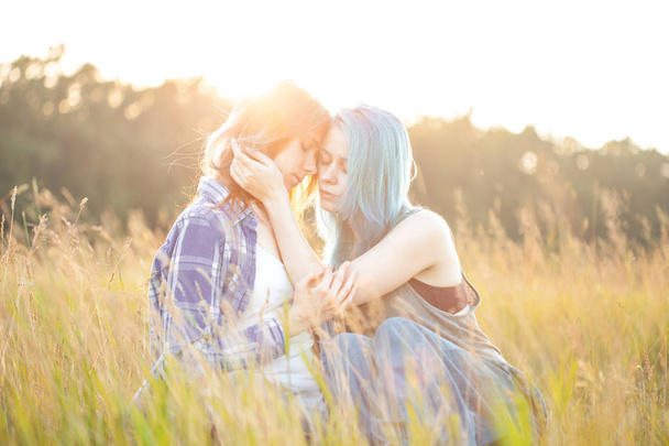 Две красивые девушки сидят в траве под солнечным светом
 - Фото, изображение