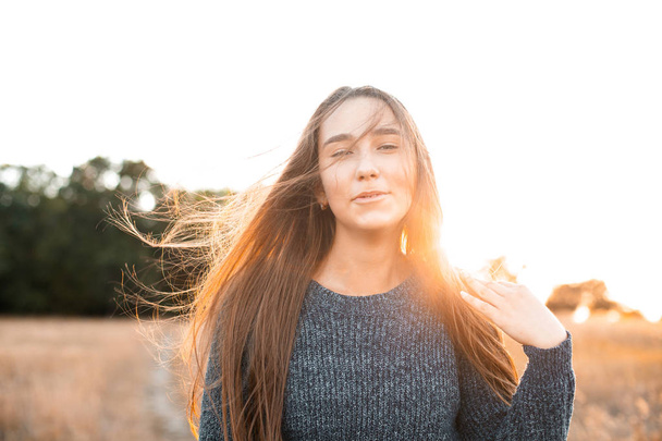 Cheerful young woman with long hair is having fun under sunlight - Фото, зображення