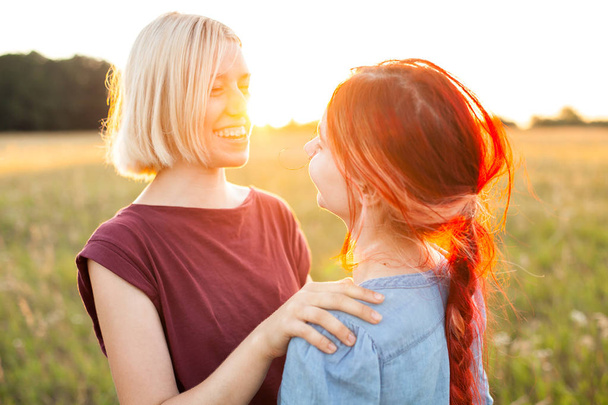 Duas meninas bonitas abraçando ao ar livre ao pôr do sol. Melhores amigos
 - Foto, Imagem