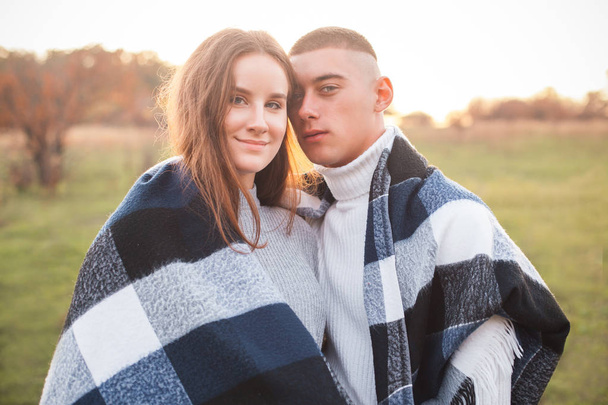 Un chico joven y una chica están al aire libre juntos, cubiertos con una manta
 - Foto, imagen