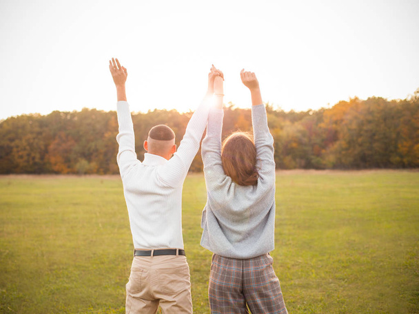 Молодий чоловік і жінка, дивлячись на захід сонця і піднімаючись руками
 - Фото, зображення