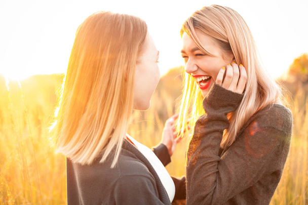 Two cheerful young woman having fun outdoors at sunset - Photo, Image