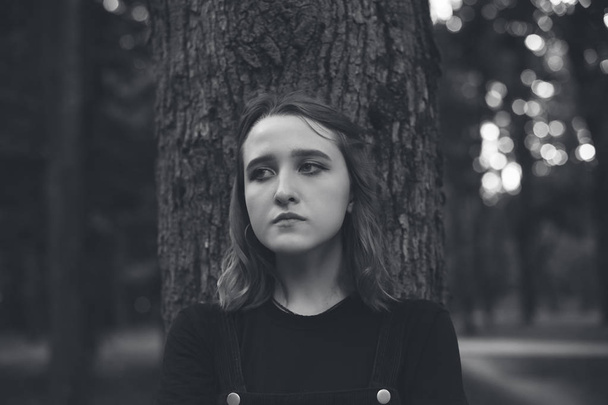 Young woman standing near the tree. Black and white - Fotografie, Obrázek