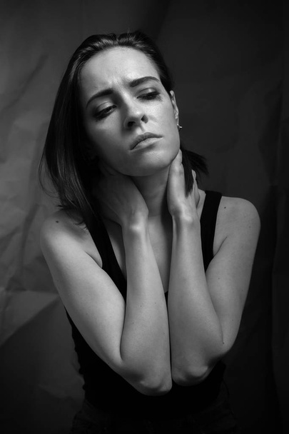 Portrait of sad young woman in studio. Black and white. - Фото, изображение