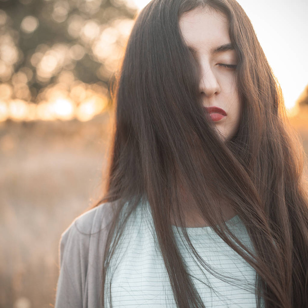Portrait of a young woman with closed eyes outdoors at evening - Foto, Imagen