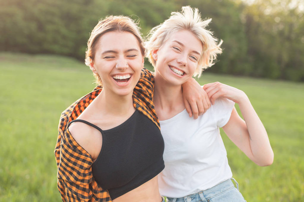 Two cheerful young women having fun on the green field. Best friends - Фото, изображение