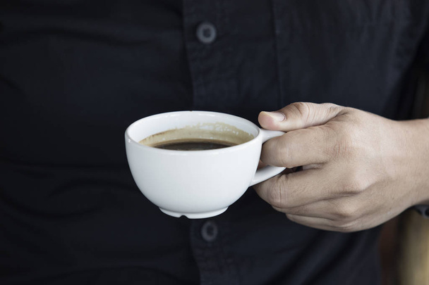 Mani di un uomo con una tazza di caffè bianco al mattino, sfondo camicia nera, Primo piano
 - Foto, immagini