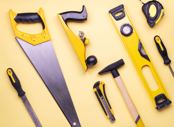 Flat layout: a set of hand tools for construction and repair on a yellow background. - Фото, изображение