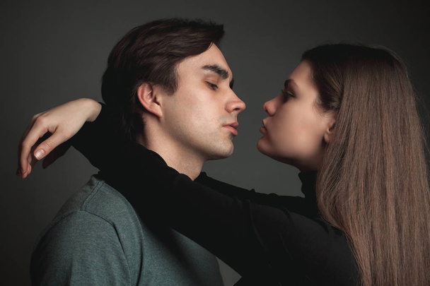 A young man and girl are hugging on a gray background - Fotoğraf, Görsel