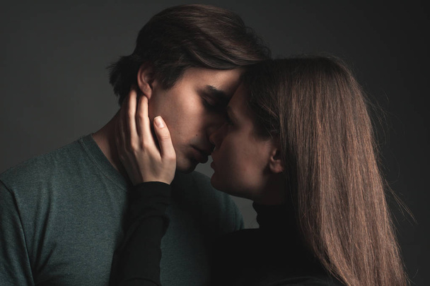 A young man and girl are kissing on a gray background - Foto, afbeelding