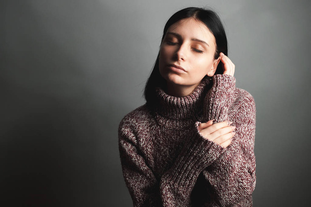 Beautiful young woman in sweater. Eyes closed - 写真・画像