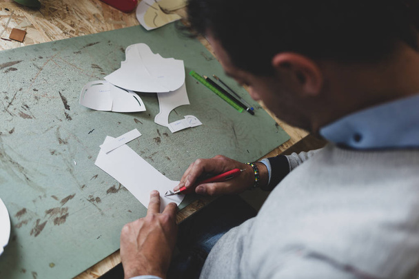 Designer de chaussures travaillant avec des modèles de papier pour la coupe du cuir
. - Photo, image