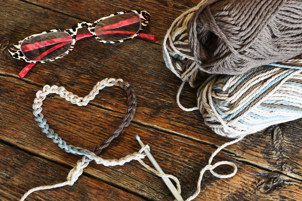 Uma imagem de perto de um único gancho de crochê e fios de crochê em um símbolo em forma de coração
. - Foto, Imagem