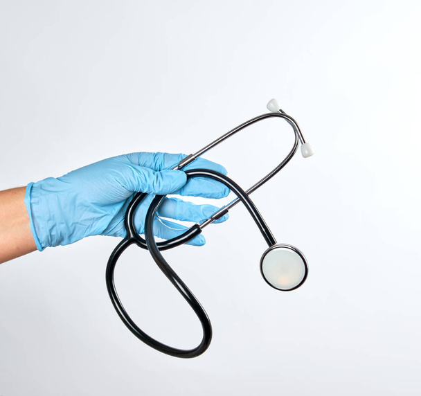 blue sterile gloved hand holding a green  stethoscope  - Foto, Bild