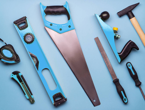 Flat layout: a set of hand tools for construction and repair on a blue background. - Photo, image