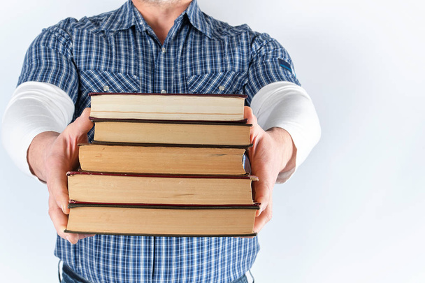 hombre de camisa a cuadros azul sosteniendo una pila de libros
  - Foto, imagen