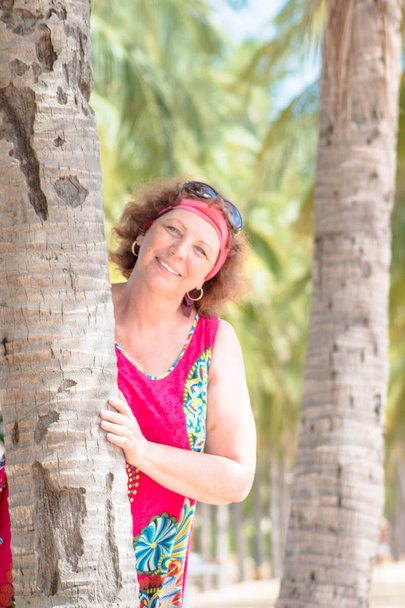 Portrait of a smiling happy senior woman standing near the palm tree - Φωτογραφία, εικόνα