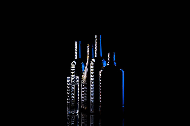 Натюрморт зі скляними пляшками на темному тлі
 - Фото, зображення