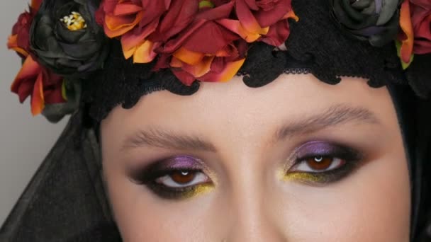 Modelo de menina profissional com belas poses de maquiagem em um boné preto e grinalda na cabeça na frente da câmera em fundo preto na imagem de uma viúva negra. De alta moda
 - Filmagem, Vídeo