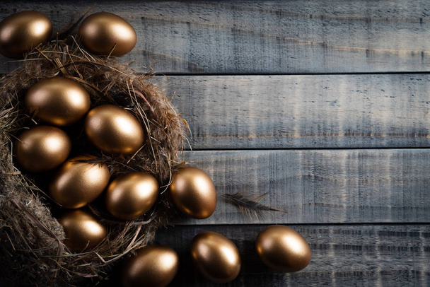 Buona Pasqua! d'oro di uova di Pasqua in nido e piuma su legno
 - Foto, immagini