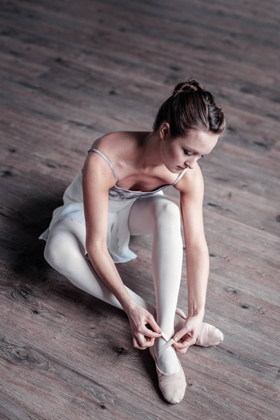 Beautiful young ballet dancer sitting on the floor - Фото, изображение