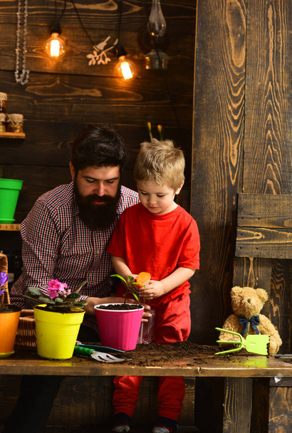 Family day. Greenhouse. bearded man and little boy love nature. Father and son. Fathers day. happy gardeners with spring flowers. Flower care watering. Soil fertilizers. Do everything with love - Fotoğraf, Görsel