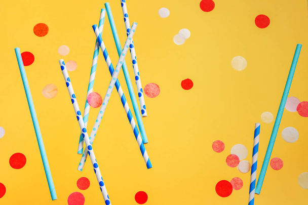 Colorful drinking straws for beverage and colored confetti on bright yellow background - Foto, Imagem