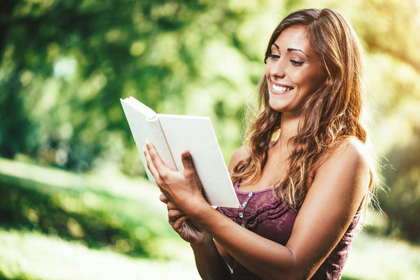 молода жінка читає книгу у весняному парку
 - Фото, зображення