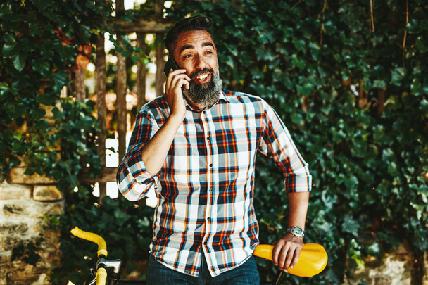 Homem de negócios casual com bicicleta falando no smartphone
. - Foto, Imagem