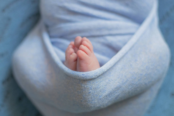 little baby legs in blue blanket on the bed at home - Foto, afbeelding