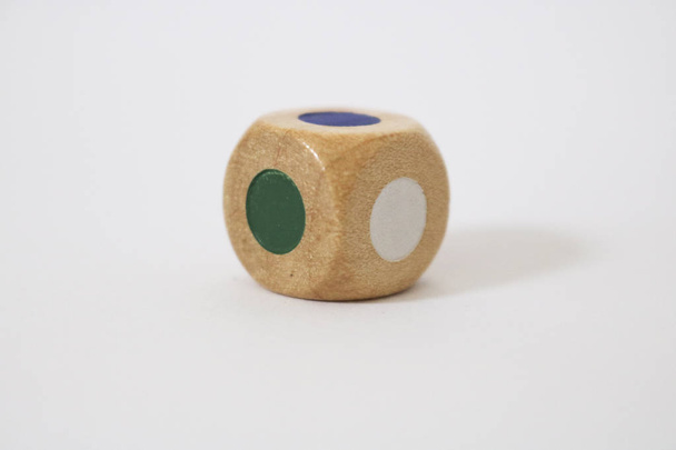 Close-up of a wooden dice with faces of different colors, on a white background, parlor games - Photo, Image