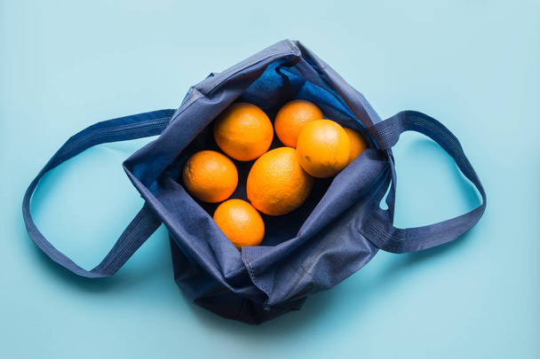 Zero waste concept. Blue shopping textile bag with fresh orange and vegetables. Space for text. - Photo, Image