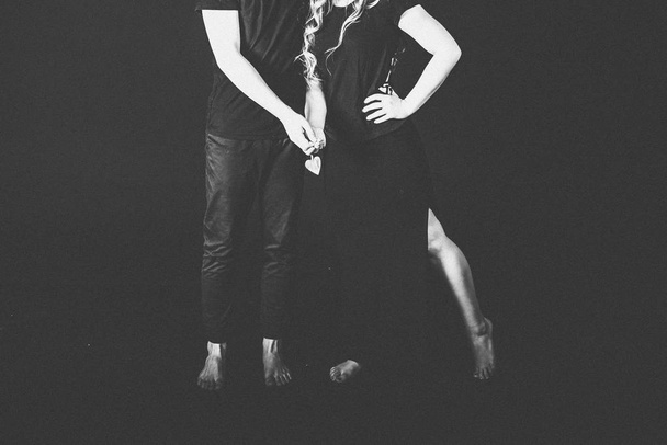 cropped view of young lovely couple posing in studio on black background  - Φωτογραφία, εικόνα