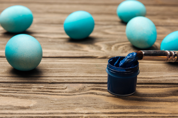 selective focus of pastel blue easter eggs, paints and paintbrush on wooden surface - Photo, Image