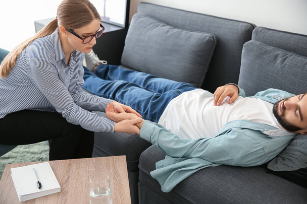 Женщина-психолог работает с пациенткой, лежащей на диване в своем кабинете
 - Фото, изображение