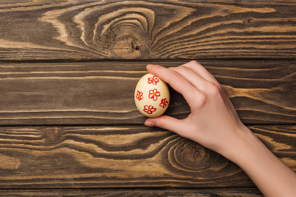 top view of woman holding easter egg with pattern on wooden surface with copy space - Fotoğraf, Görsel