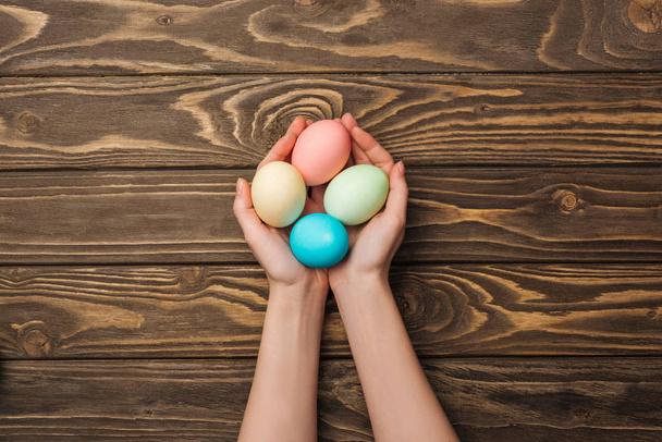 felülnézet nő gazdaság pasztell húsvéti tojás fa felülettel - Fotó, kép